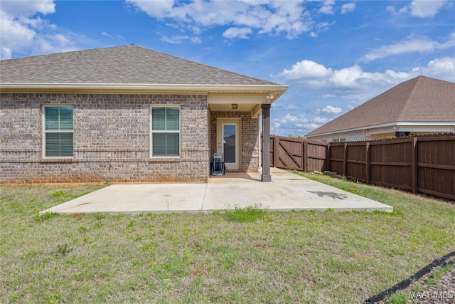 rear view of house featuring brick siding, a fenced backyard, and a patio