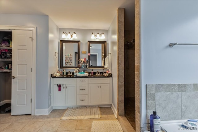 bathroom with double vanity, tile patterned floors, tiled shower, and a sink
