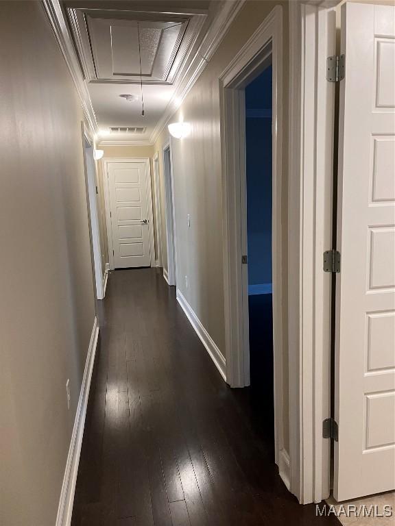 hall featuring attic access, dark wood finished floors, baseboards, visible vents, and crown molding