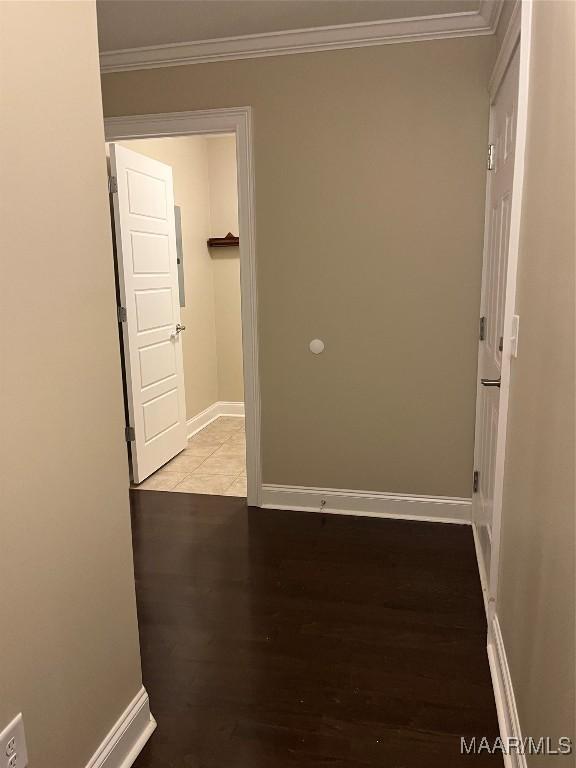 corridor featuring wood finished floors, baseboards, and ornamental molding