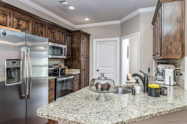 1017 Ridge Point Dr, Deatsville, AL 36022 - kitchen with stainless steel appliances, a peninsula, visible vents, dark brown cabinetry, and ornamental molding