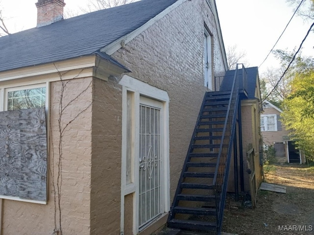 12 E Fairview Ave, Montgomery, AL 36105 - view of side of property with a shingled roof, a chimney, stairs, and stucco siding