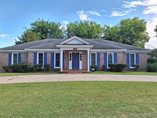 view of front facade with brick siding, a front lawn, and roof with shingles