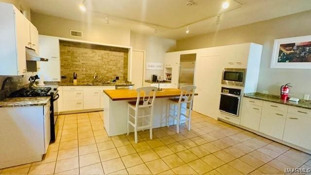kitchen featuring visible vents, appliances with stainless steel finishes, under cabinet range hood, rail lighting, and light tile patterned floors