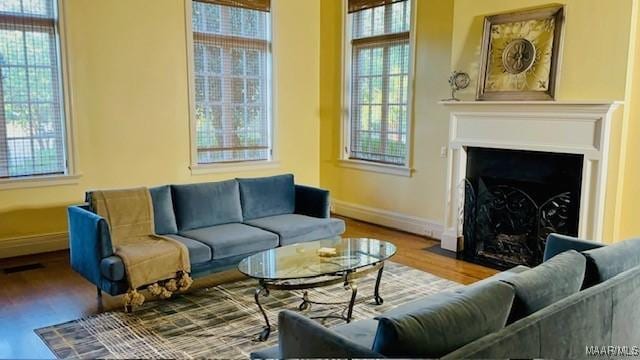 living area with a fireplace with flush hearth, baseboards, and wood finished floors
