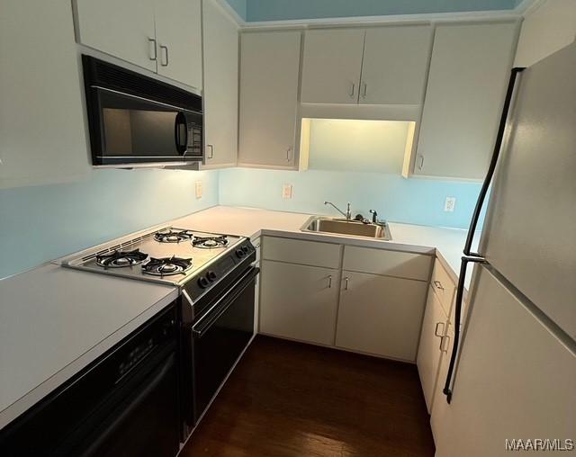 kitchen featuring a sink, black microwave, gas range, light countertops, and freestanding refrigerator