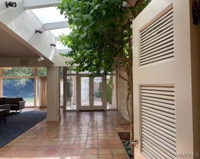 entryway with french doors, light tile patterned flooring, decorative columns, and a heating unit