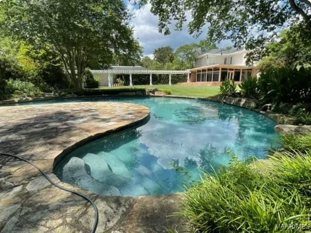 outdoor pool featuring a lawn and a sunroom