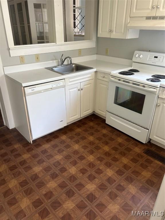 kitchen featuring white cabinets, under cabinet range hood, a sink, and white appliances