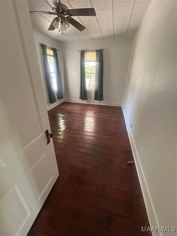 unfurnished room featuring dark wood-type flooring, baseboards, and ceiling fan