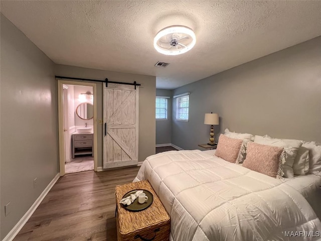 113 Kingston Pl, Prattville, AL 36067 - bedroom featuring a barn door, dark wood-style flooring, baseboards, visible vents, and a textured ceiling