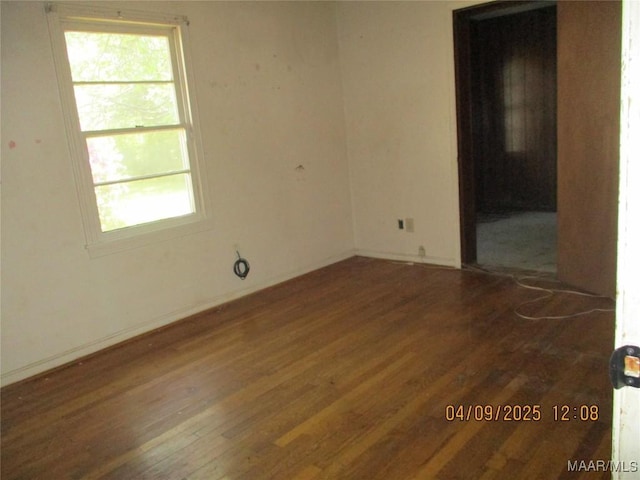 empty room featuring baseboards, wood finished floors, and a healthy amount of sunlight