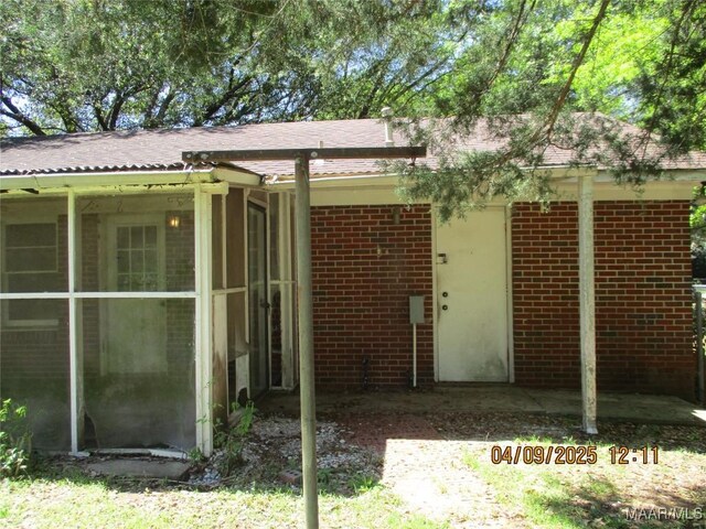 rear view of property featuring brick siding and a sunroom