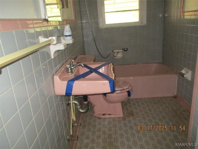 full bathroom featuring toilet, tile walls, and a sink