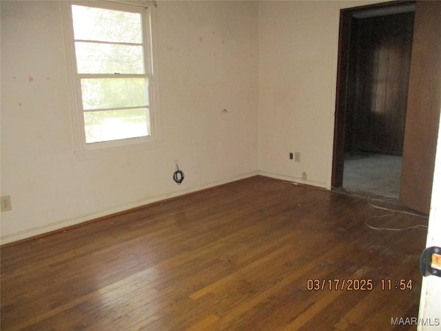 unfurnished room featuring baseboards and dark wood-type flooring