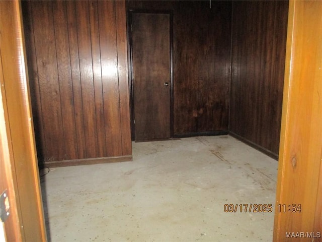 empty room with wood walls and unfinished concrete floors