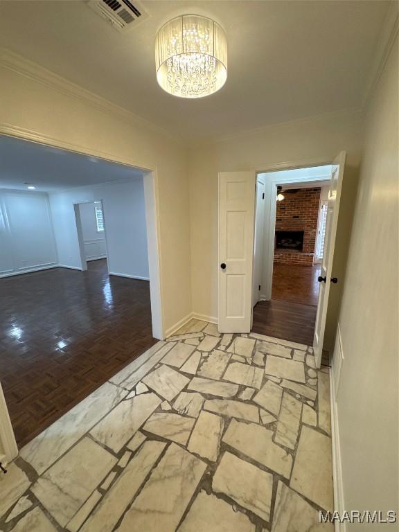 spare room with crown molding, a notable chandelier, visible vents, and baseboards