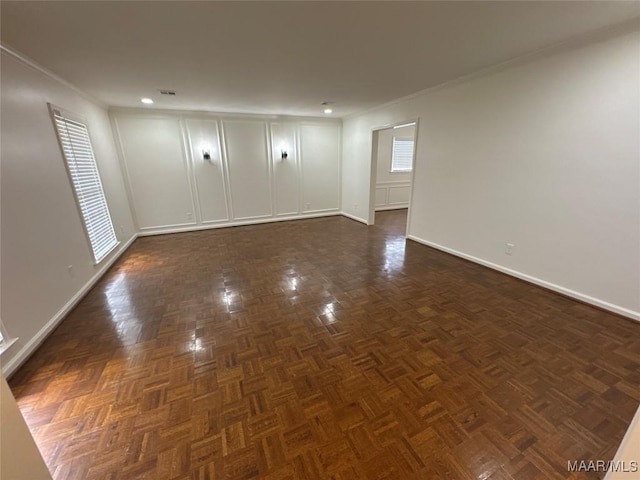 empty room featuring crown molding and baseboards