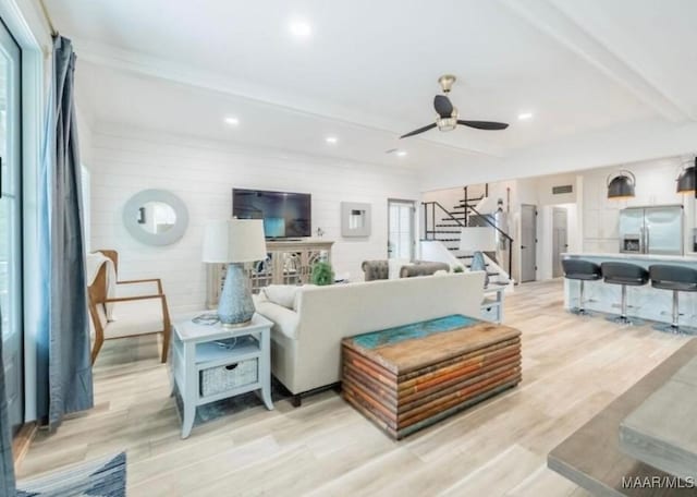 living area featuring beamed ceiling, recessed lighting, stairway, ceiling fan, and light wood-type flooring