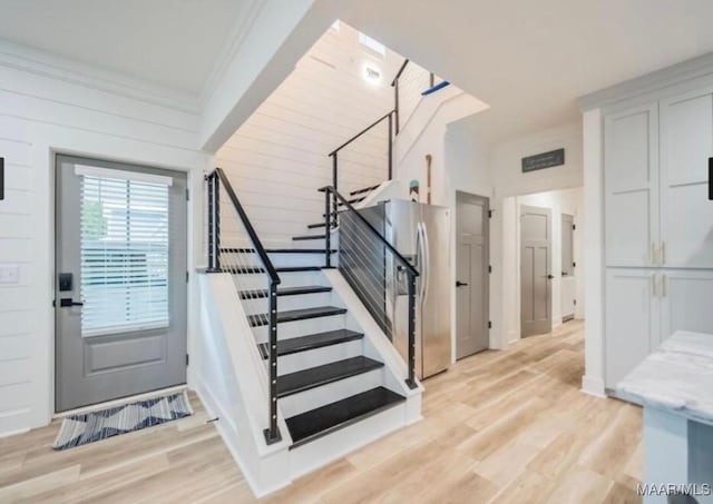 staircase with crown molding and wood finished floors
