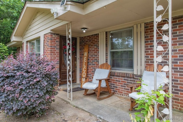 property entrance with covered porch and brick siding