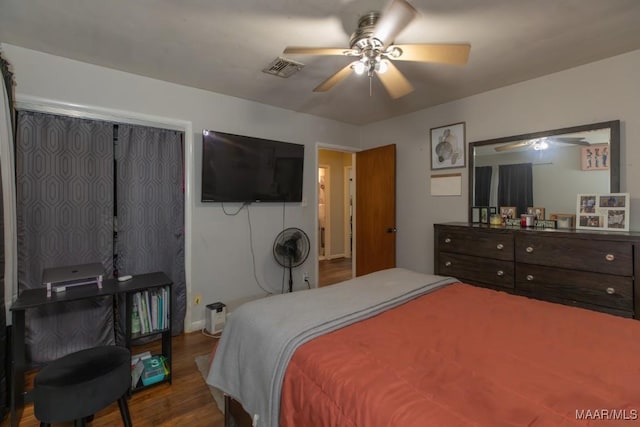 bedroom featuring a ceiling fan, visible vents, wood finished floors, and baseboards