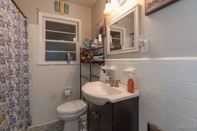 bathroom with tile walls, vanity, toilet, a wainscoted wall, and a shower with shower curtain