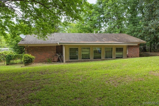 back of house featuring a yard and brick siding