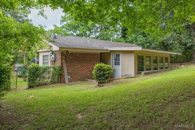 back of property featuring brick siding, fence, a yard, and roof with shingles