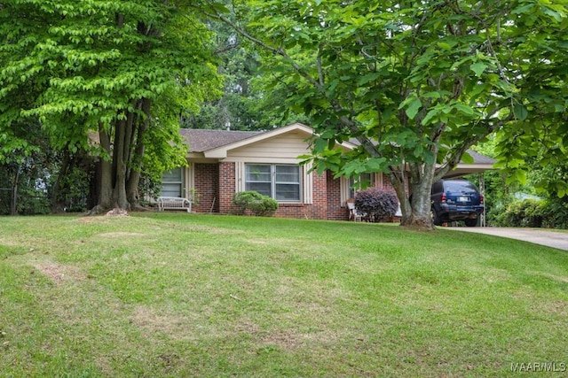 view of front facade featuring concrete driveway, a front yard, brick siding, and an attached carport