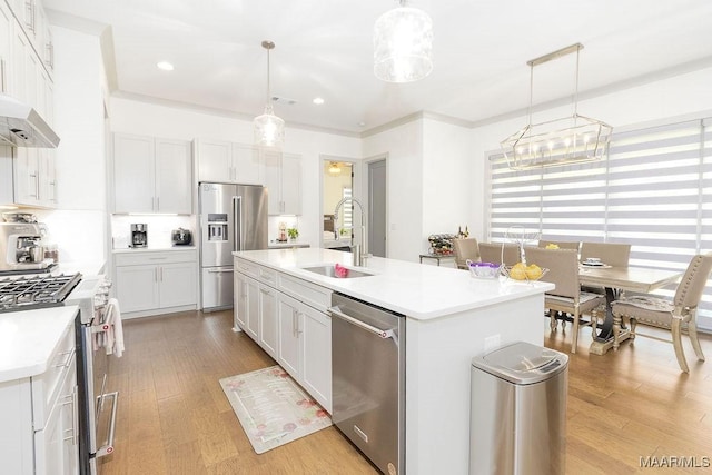 kitchen featuring light wood finished floors, a sink, premium appliances, light countertops, and an island with sink