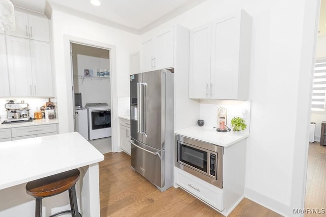 kitchen featuring white cabinets, light wood-style floors, appliances with stainless steel finishes, and light countertops