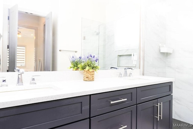 full bathroom with double vanity, walk in shower, a ceiling fan, and a sink