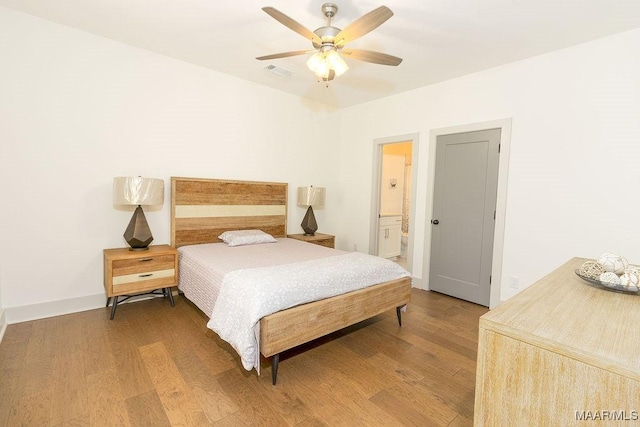 bedroom with connected bathroom, visible vents, ceiling fan, and wood finished floors