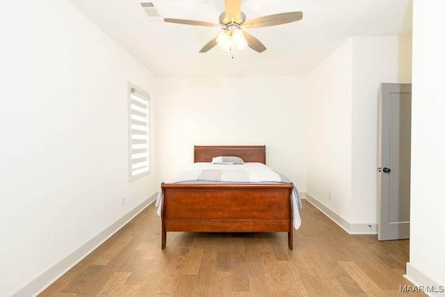 bedroom with light wood finished floors, a ceiling fan, visible vents, and baseboards