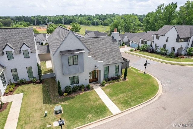 view of front of house featuring a shingled roof, a residential view, and a front yard