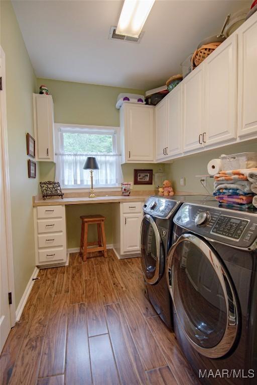 laundry room with visible vents, wood finished floors, washer and dryer, and cabinet space