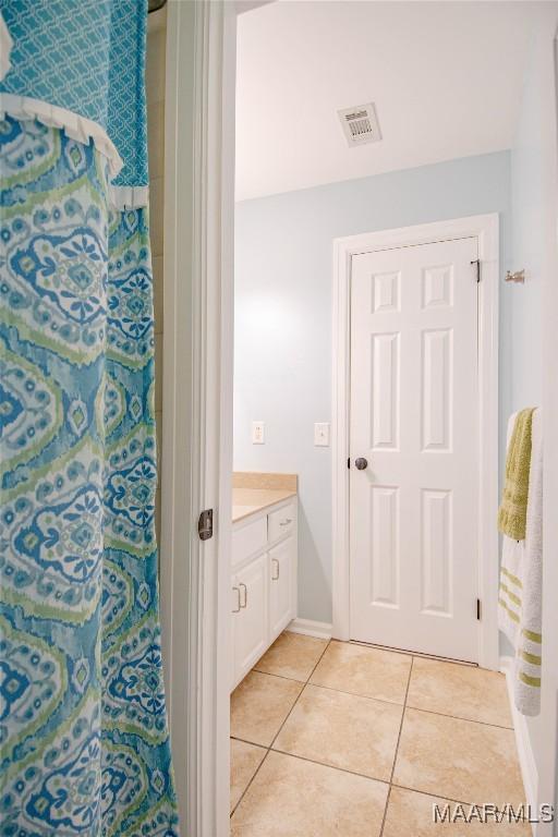 bathroom featuring vanity, curtained shower, visible vents, baseboards, and tile patterned flooring