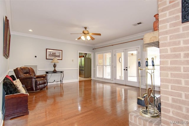 sitting room featuring wood finished floors, visible vents, ceiling fan, and ornamental molding