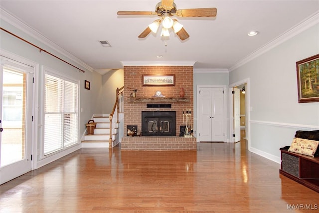 living room with light wood finished floors, stairway, ceiling fan, visible vents, and ornamental molding