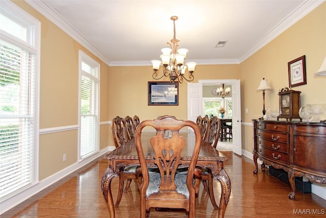dining room with an inviting chandelier, visible vents, baseboards, ornamental molding, and wood finished floors
