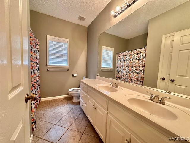 bathroom with visible vents, toilet, double vanity, and a sink
