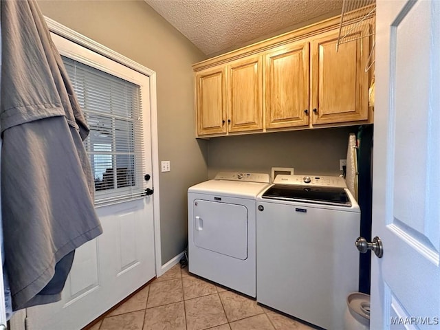 clothes washing area featuring light tile patterned floors, washing machine and dryer, a textured ceiling, and cabinet space