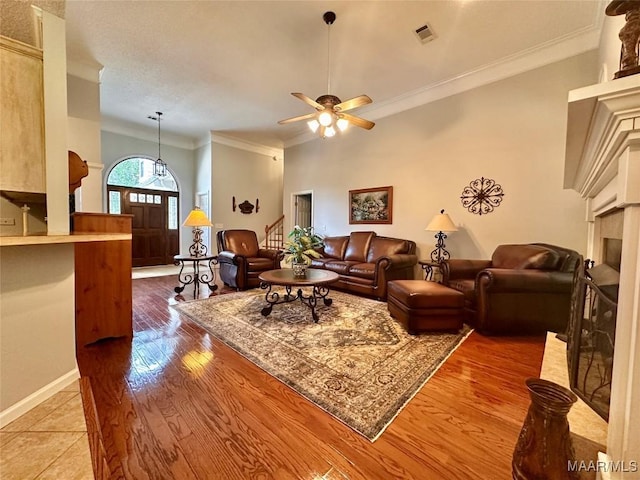 living area with visible vents, ornamental molding, ceiling fan, and a fireplace