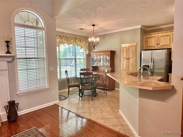 dining space with a textured ceiling, crown molding, light wood-style floors, baseboards, and an inviting chandelier