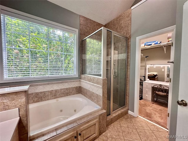 bathroom with a textured ceiling, a whirlpool tub, tile patterned flooring, and a stall shower
