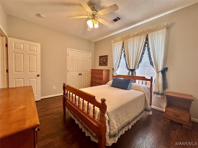 bedroom featuring baseboards, visible vents, a textured ceiling, and dark wood finished floors