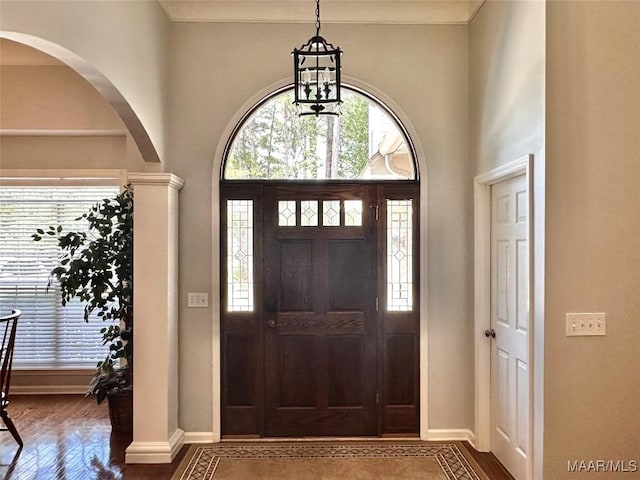 foyer entrance with a towering ceiling, wood finished floors, baseboards, and arched walkways