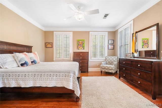 100 S Franklin Ave, Luverne, AL 36049 - bedroom featuring crown molding, ceiling fan, baseboards, wood finished floors, and visible vents