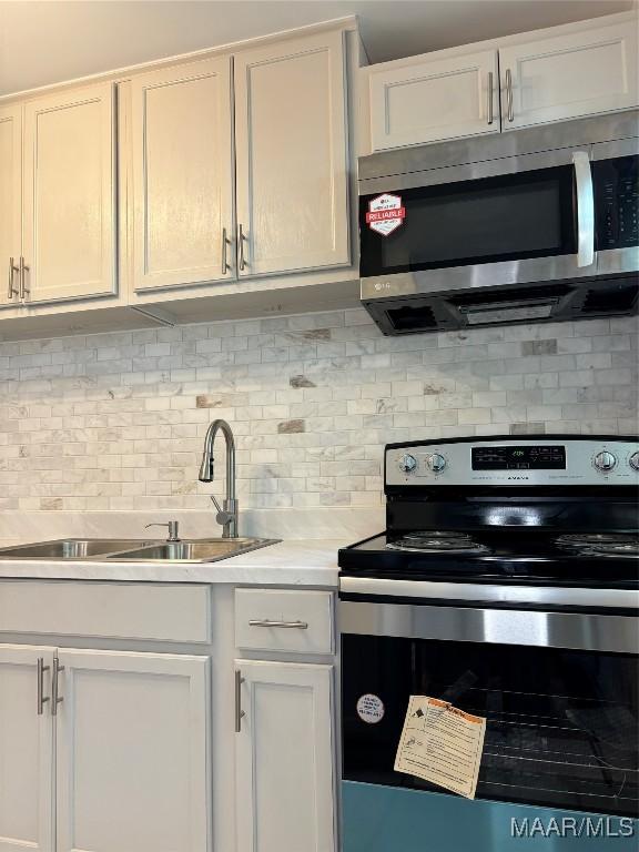 644 Iris Ln, Montgomery, AL 36105 - kitchen featuring appliances with stainless steel finishes, tasteful backsplash, light countertops, and white cabinetry